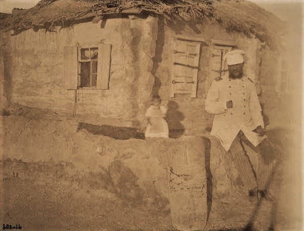Sergiopol. A stone figure near the house of Mikhail Chernov in Sergiopol. Photographer: Nikolai Nikolaevich Pantusov, a renowned Russian archaeologist, orientalist, and ethnographer. July 1898. A carved stone - a so-called “kamennaya baba” - lies on the ground in front of the administration building, with Cossacks sitting on it. In 1898, the orientalist and archaeologist N. N. Pantusov described these “balbals” (“kamennye baby”) in Sergiopol settlement and even photographed many of them.