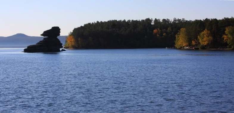 Zhumbaktas Rock, located in Blue Bay of Lake Burabay in Burabay Park. Zhumbaktas Rock is one of main natural attractions of Borovoe Resort. Its name translates as "mystery rock" or "riddle stone." Depending on viewing angle, rock's outline changes: it can resemble a boat floating on a lake, or profile of a young girl with flowing hair. Many local legends and tales are associated with this rock.