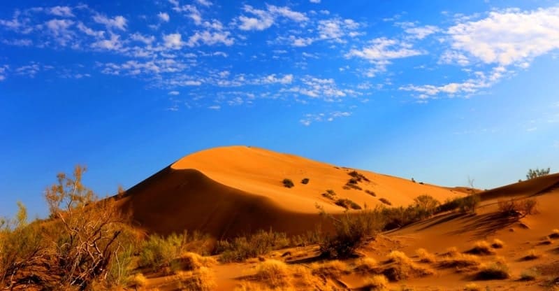 The sand massif is located between mountains: Kysty-Kalkan in the west, with a dominant elevation of 956.8 meters above sea level, and Ulken-Kalkan in the east, with a highest elevation of 1,281 meters above sea level.