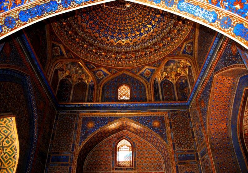Mihrab section of the Tillya-Kari Madrasah. The ceiling and dome are richly decorated with intricate geometric and floral patterns.